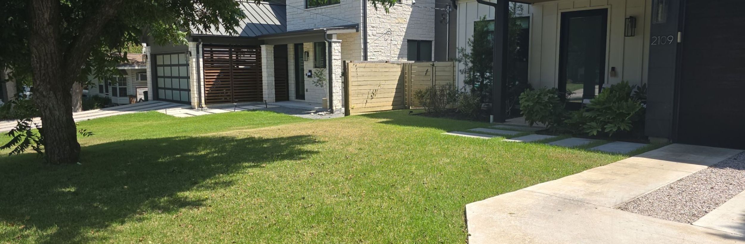 Healthy green front lawn with a concrete walkway and stepping stones at a modern Austin home