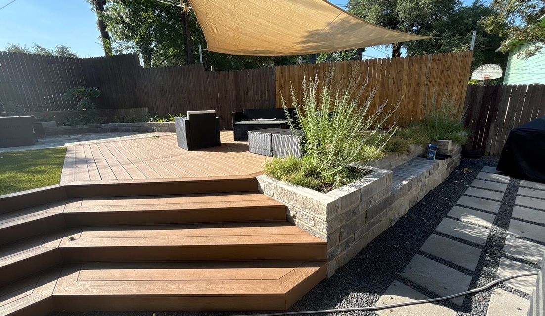 Composite deck with wide wraparound steps and a limestone block planter built by GardenGOAT in Austin