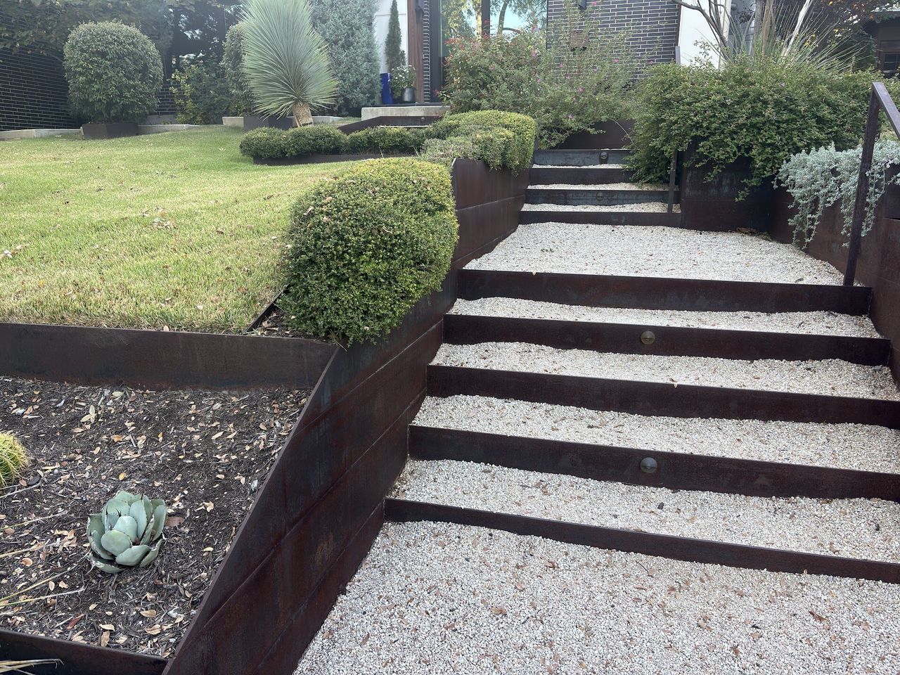 Gravel steps with corten steel risers and terraced planting beds in an Austin xeriscape