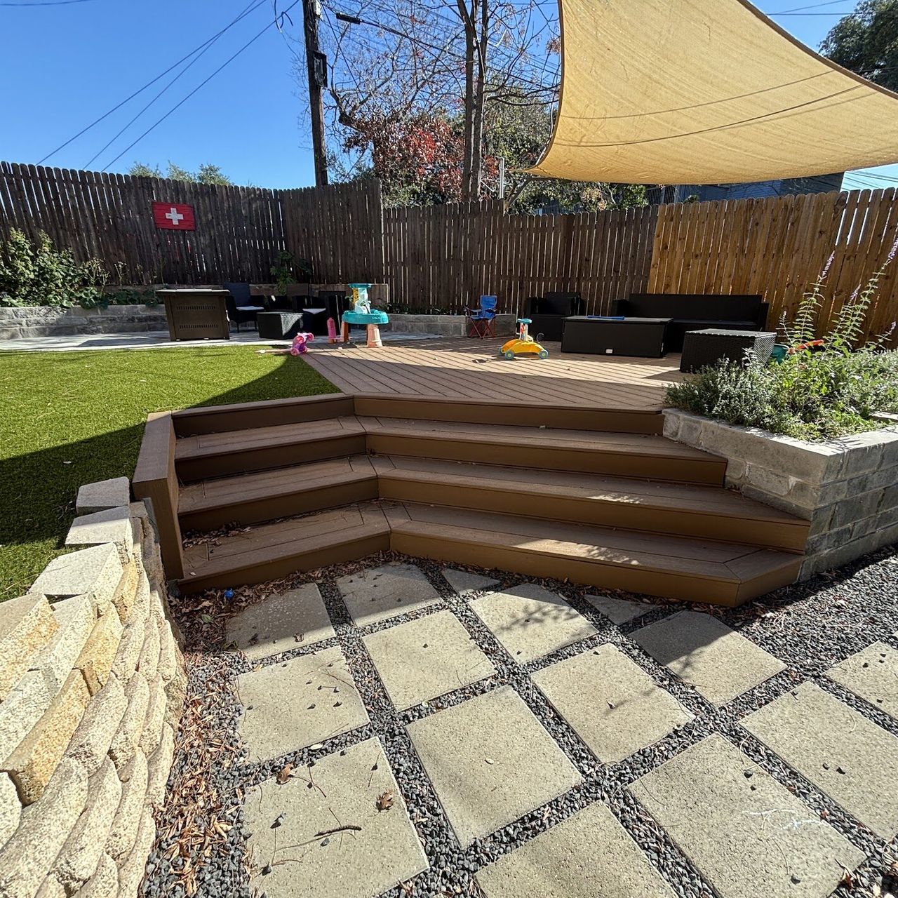 Low-maintenance composite deck with wide wraparound steps next to artificial turf in Austin