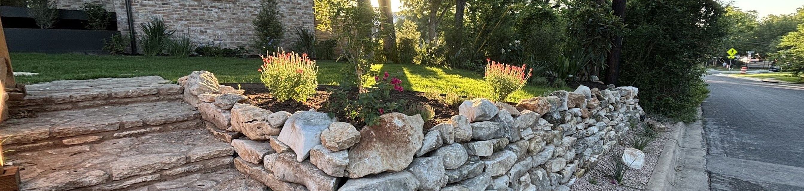 Dry-stacked limestone retaining wall and natural stone steps built by GardenGOAT in Austin