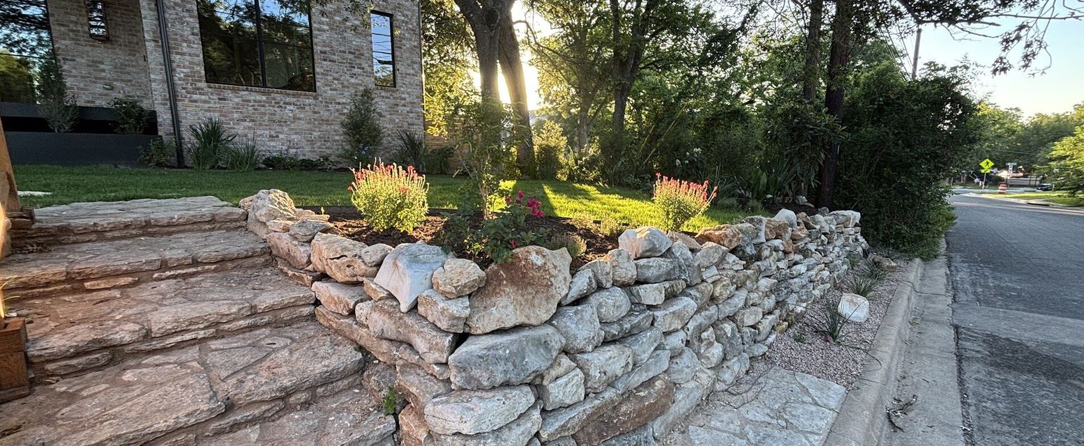 Dry-stacked limestone retaining wall and natural stone steps built by GardenGOAT in Austin