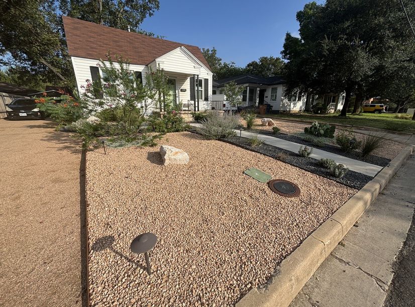 Front yard xeriscape with crushed granite, a boulder, and native plants in Austin