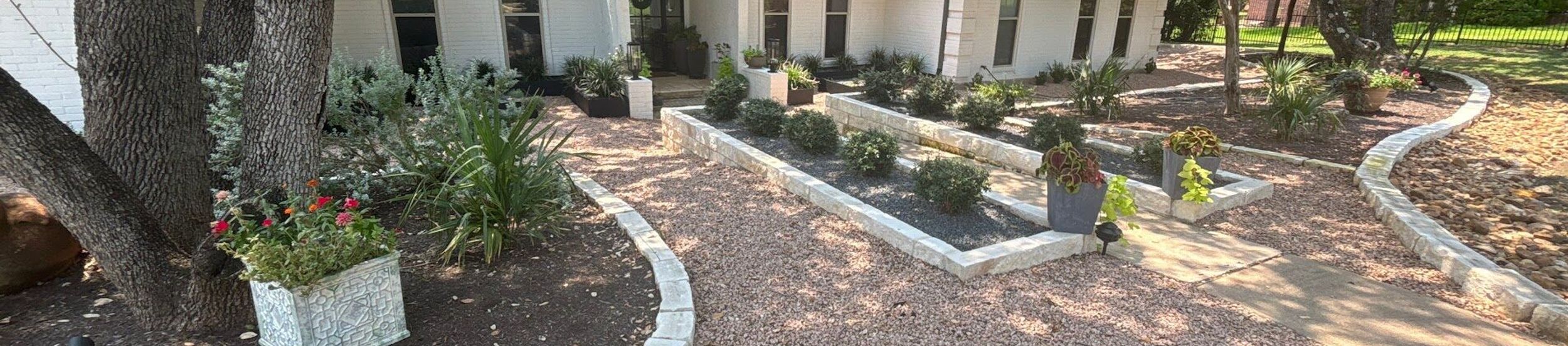 Front yard xeriscape with crushed granite, limestone block borders, and drought-tolerant planting beds at an Austin home