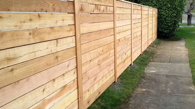 Horizontal wood privacy fence running alongside a sidewalk and grass strip