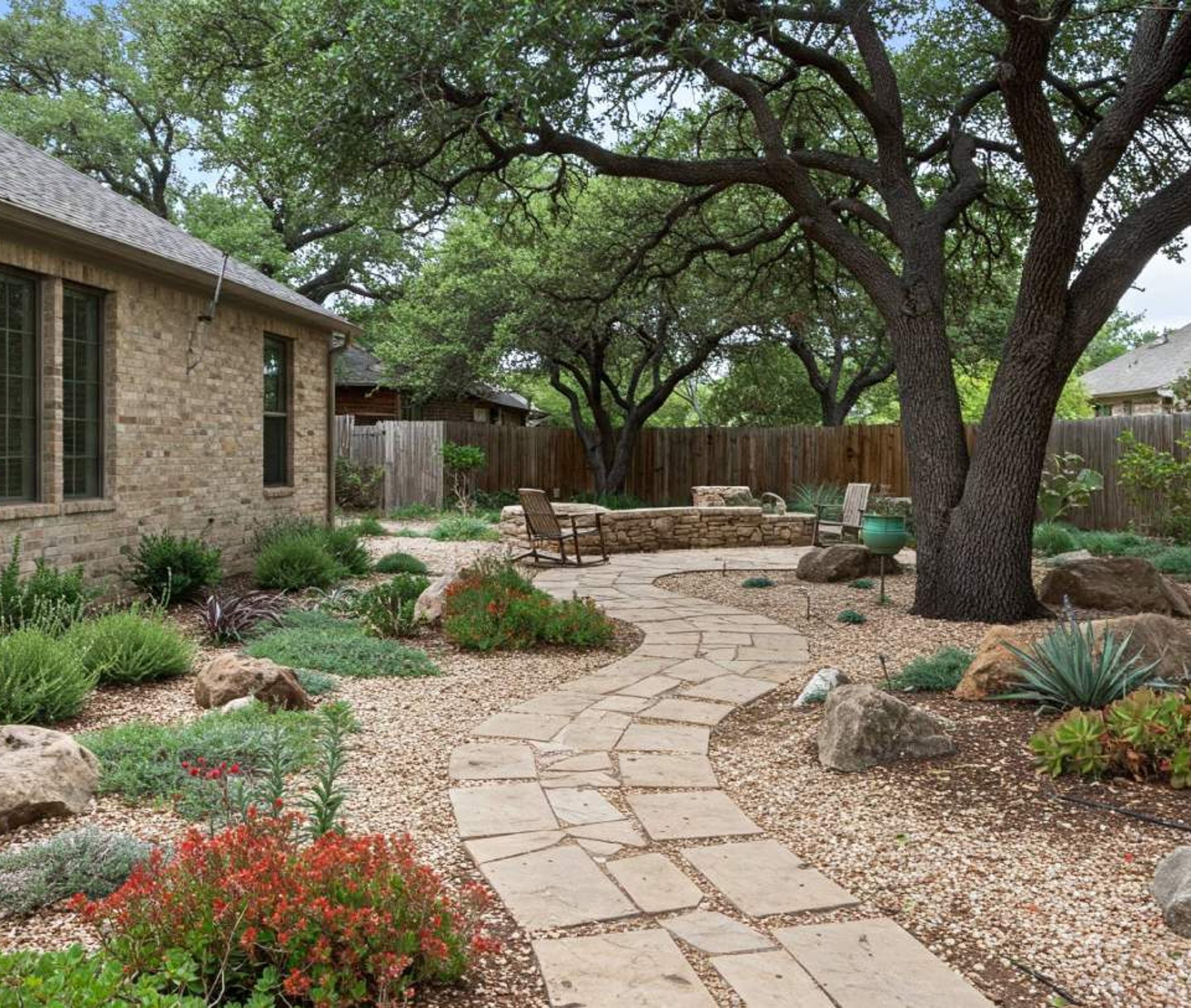 Flagstone pathway through a xeriscape garden with native plants and live oaks in Austin