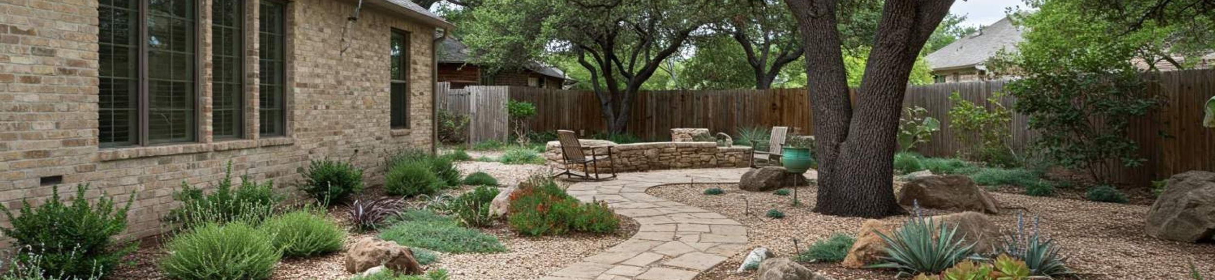 Flagstone pathway through a xeriscape garden with native plants and live oaks in Austin