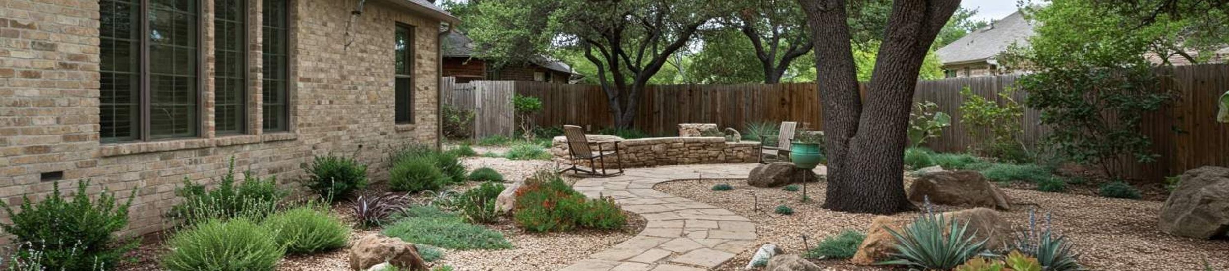 Flagstone pathway through a xeriscape garden with native plants and live oaks in Austin