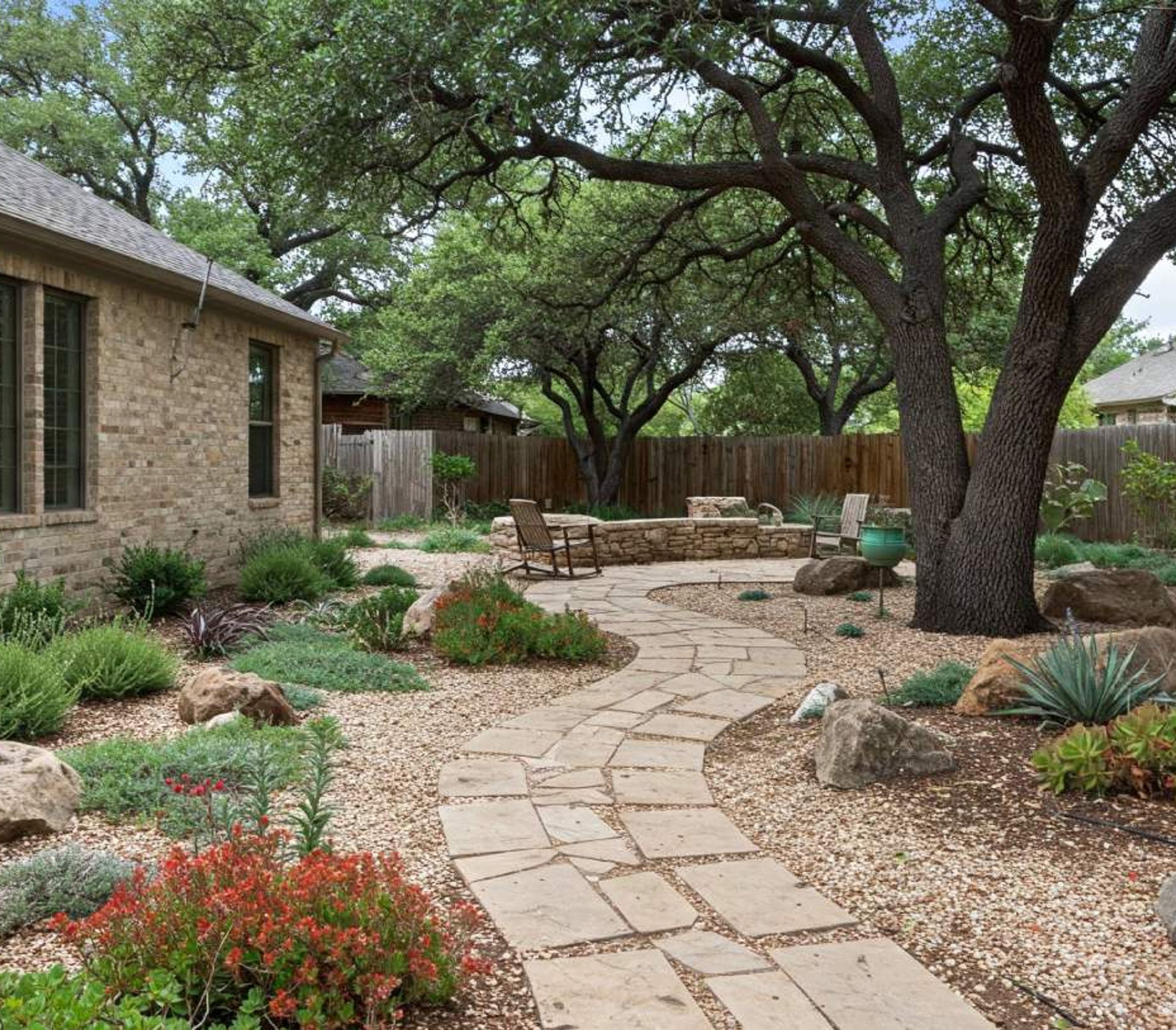 Flagstone pathway through a xeriscape garden with native plants and live oaks in Austin