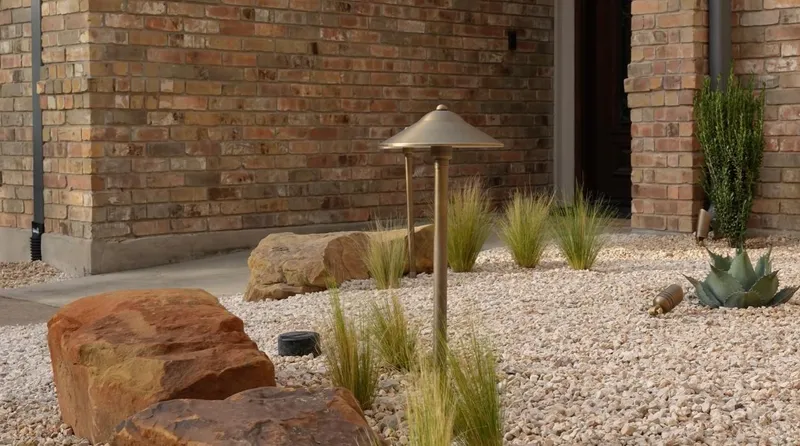 Path light and accent fixtures among gravel, sandstone boulders, and plants at the Indigo project