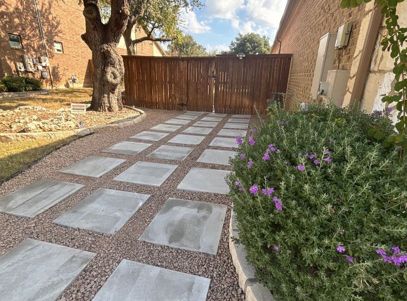 Concrete paver and gravel side-yard pathway leading to a cedar gate in Austin